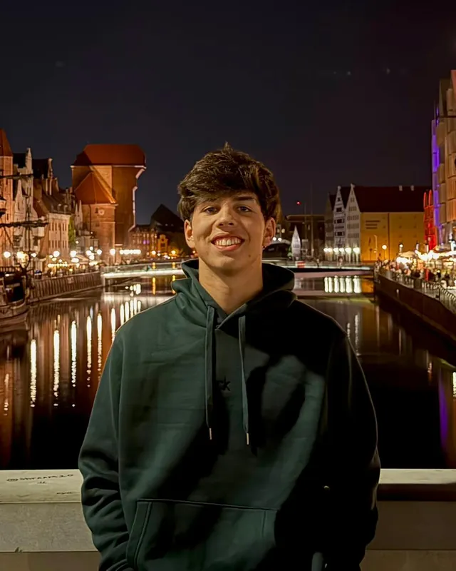 Pablo Álvaro, sonriendo, de noche junto a un canal con las casas iluminadas